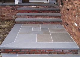 A set of stone steps leading up to a brick wall.