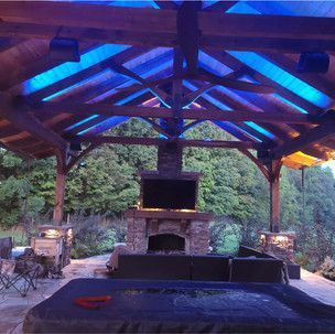 A gazebo with blue lights on the ceiling and a fireplace.