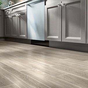 A kitchen with gray cabinets and a wooden floor.