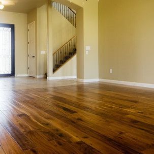 An empty living room with hardwood floors and a staircase.