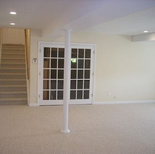 An empty basement with a staircase and french doors.