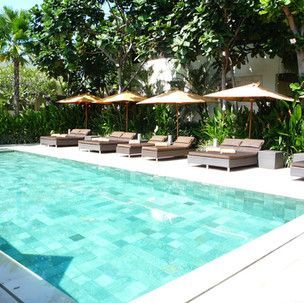 A large swimming pool surrounded by chairs and umbrellas
