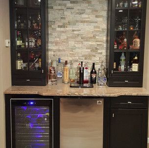 A bar with bottles of liquor and a wine cooler.