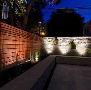 A wooden fence is lit up at night in a backyard.