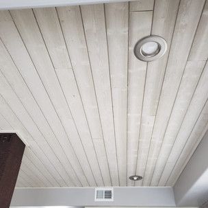 A ceiling with wood paneling and a light on it.