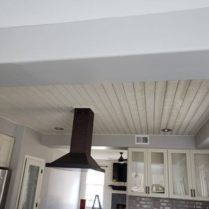 A kitchen with a stove hood hanging from the ceiling.