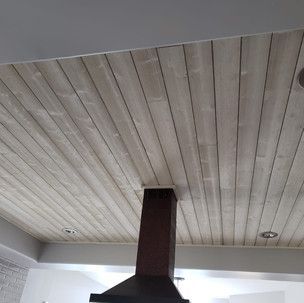 A kitchen with a wooden ceiling and a hood.