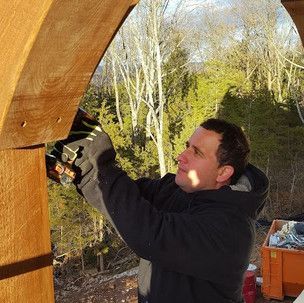 A man is working on a wooden structure with a drill.