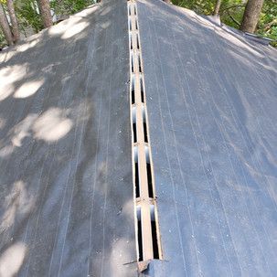 A long piece of wood is sitting on top of a roof.