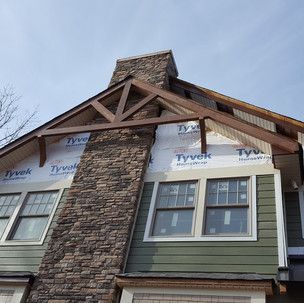 A house with green siding and a stone chimney.