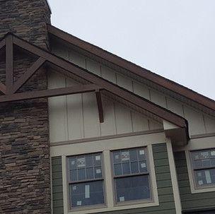 The roof of a house with a stone chimney and a lot of windows.