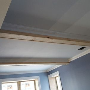 A room with blue walls and a white ceiling with wooden beams.