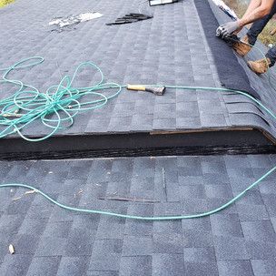 A man is working on a roof with a hose and a hammer.