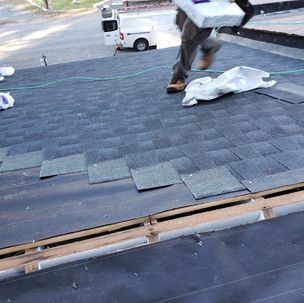 A man is carrying a box on top of a roof.
