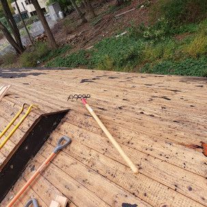 A wooden deck with a rake and shovel on it.