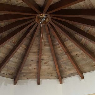 A close up of a wooden ceiling with a light hanging from it.