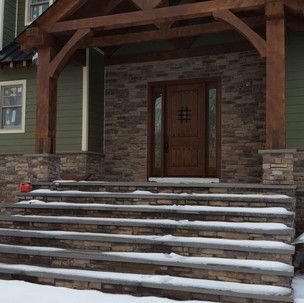 A house with a porch and stairs covered in snow.