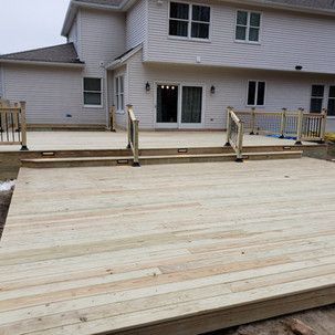 A large wooden deck is being built in front of a house.