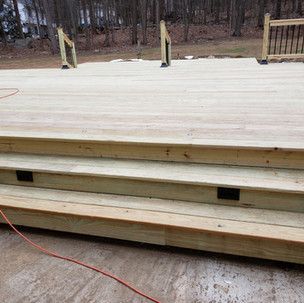 A wooden deck with stairs and a red power cord.