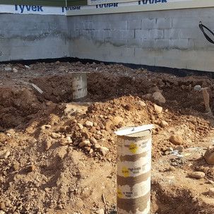 A pile of dirt is sitting in front of a brick wall.