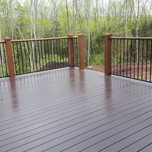 A wooden deck with a metal railing and trees in the background.