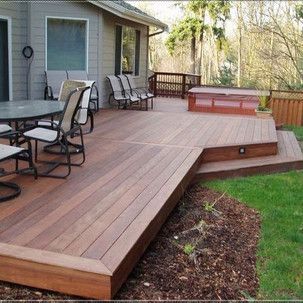 A wooden deck with a table and chairs and a hot tub.