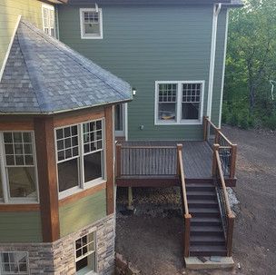A green house with a wooden deck and stairs