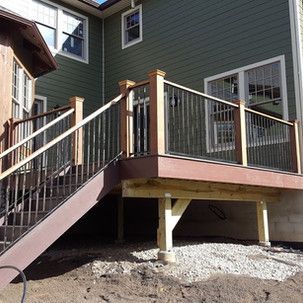 A deck with stairs leading up to it and a house in the background.