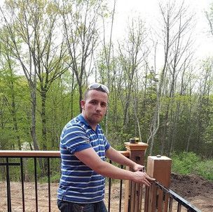 A man in a blue and white striped shirt is standing on a deck.