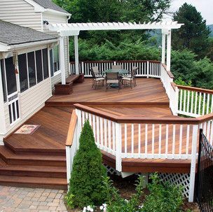 A large wooden deck with a white railing and a table and chairs on it.