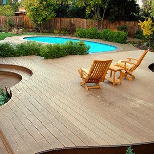 A wooden deck with chairs and a table next to a swimming pool.