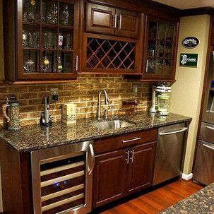 A kitchen with stainless steel appliances , granite counter tops , a sink and a wine cooler.