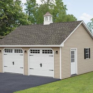 A garage with three garage doors and a chimney on the roof.