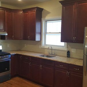 A kitchen with wooden cabinets , granite counter tops , a sink , stove and refrigerator.