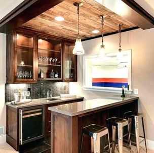 A kitchen with a bar and stools and a wooden ceiling.