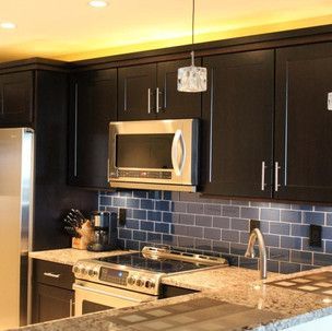 A kitchen with black cabinets and stainless steel appliances