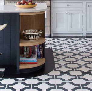 A kitchen with a black and white tile floor and a bowl of fruit on the counter.
