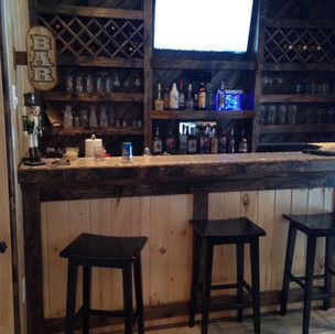 A wooden bar with stools and a tv on the wall.