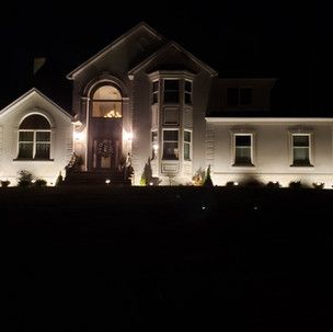 A large white house is lit up at night.