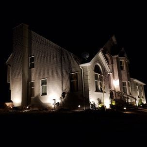 A large white house is lit up at night.