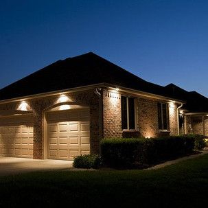 A house with two garage doors is lit up at night.