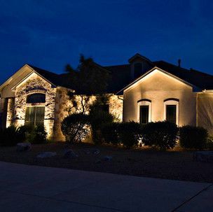 A house is lit up at night with a blue sky in the background.