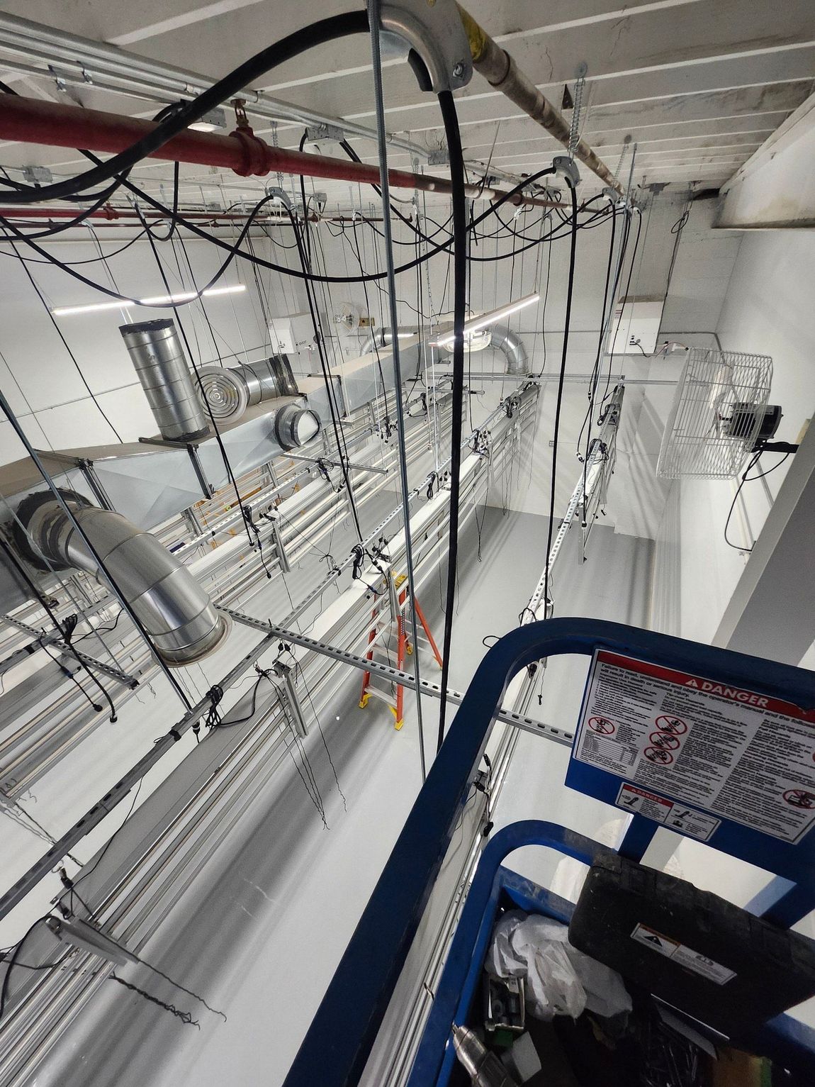 A person is standing in a room with a lot of wires hanging from the ceiling.