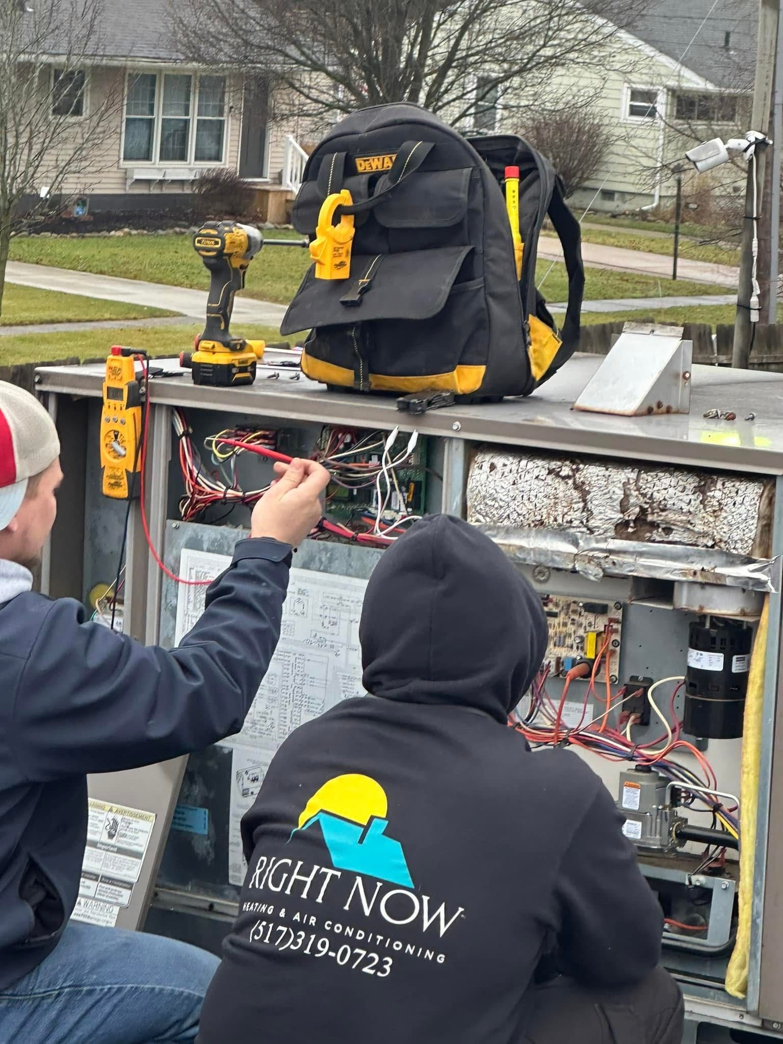 A man wearing a right now sweatshirt is working on a machine.