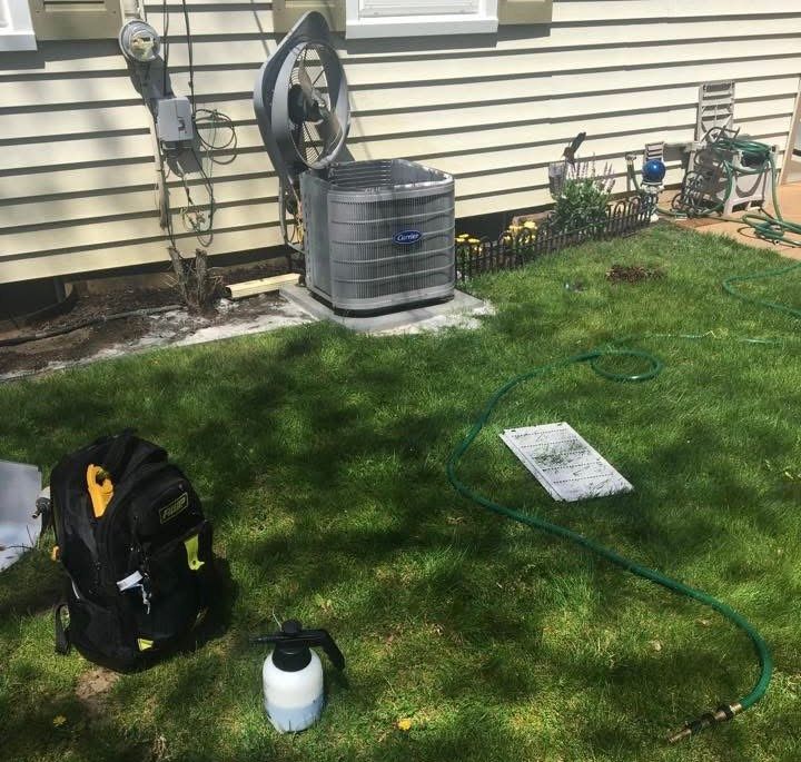 A hose is connected to an air conditioner outside of a house.