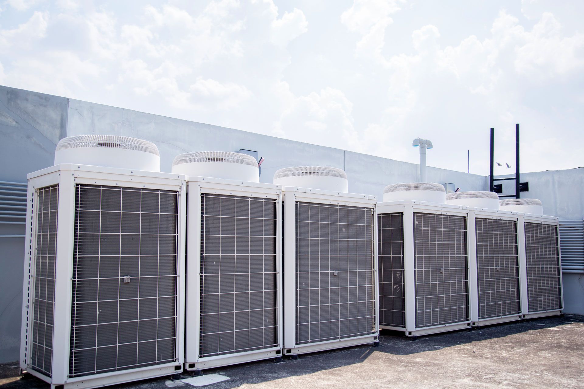 A row of air conditioners are sitting on top of a building.