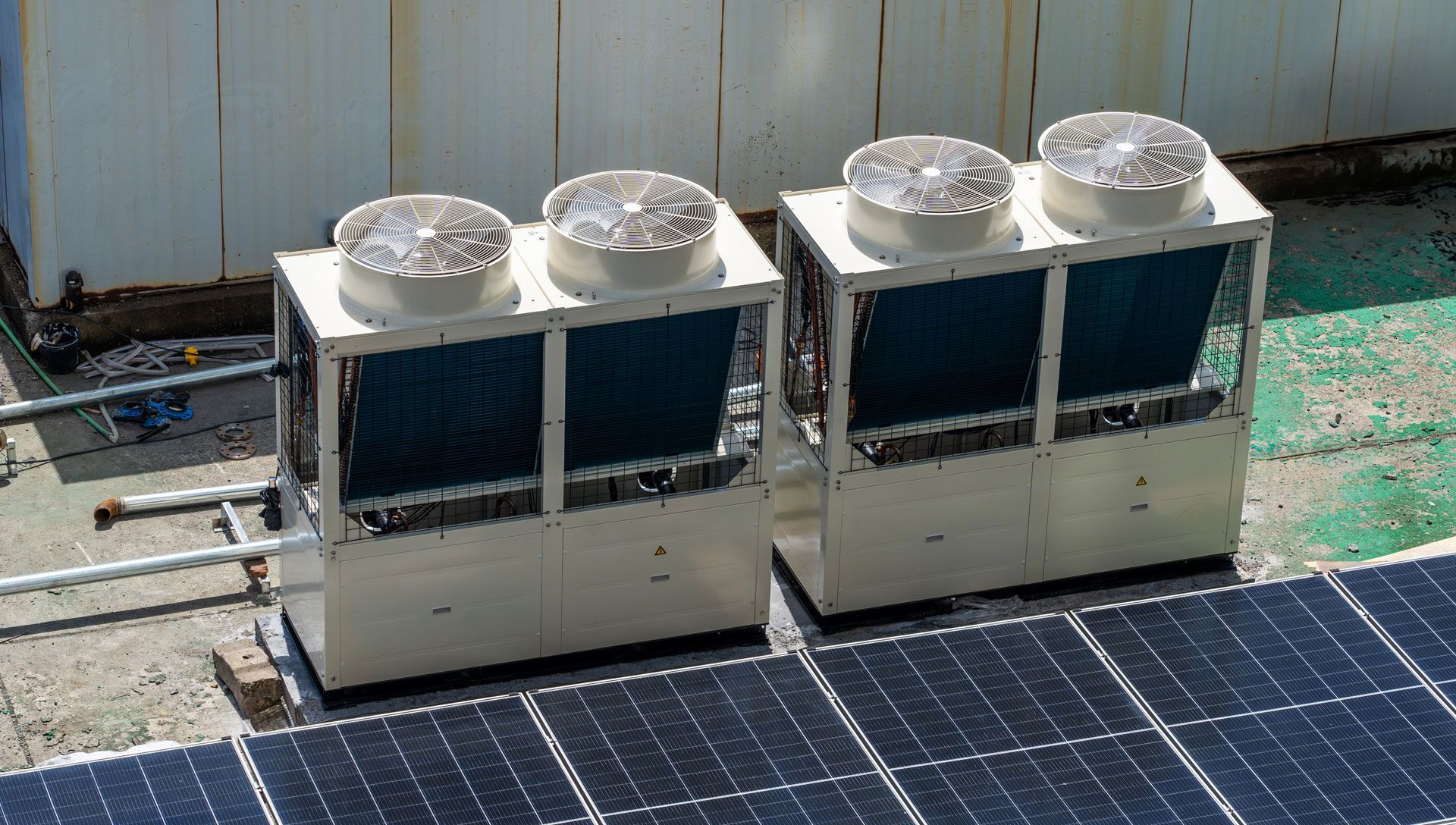 Two air conditioners are sitting on top of a solar panel.
