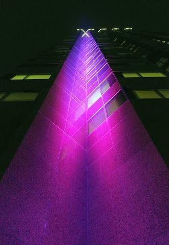 A purple light is shining on a building at night.