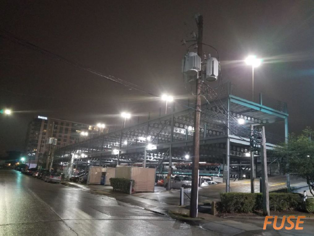 A parking garage is lit up at night in a city.