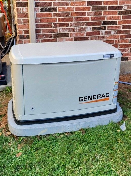A generac generator is sitting in the grass in front of a brick building.